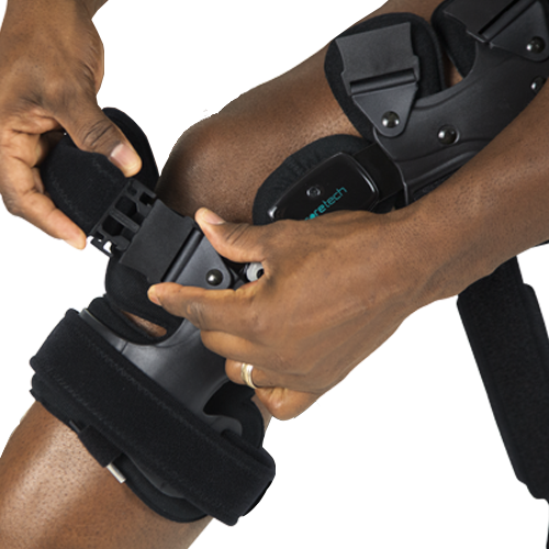 A person wearing the 845 Dual OA Knee Brace Coretech by Vive Health adjusts its straps to ensure a snug fit, aiming for improved mobility and pain relief.