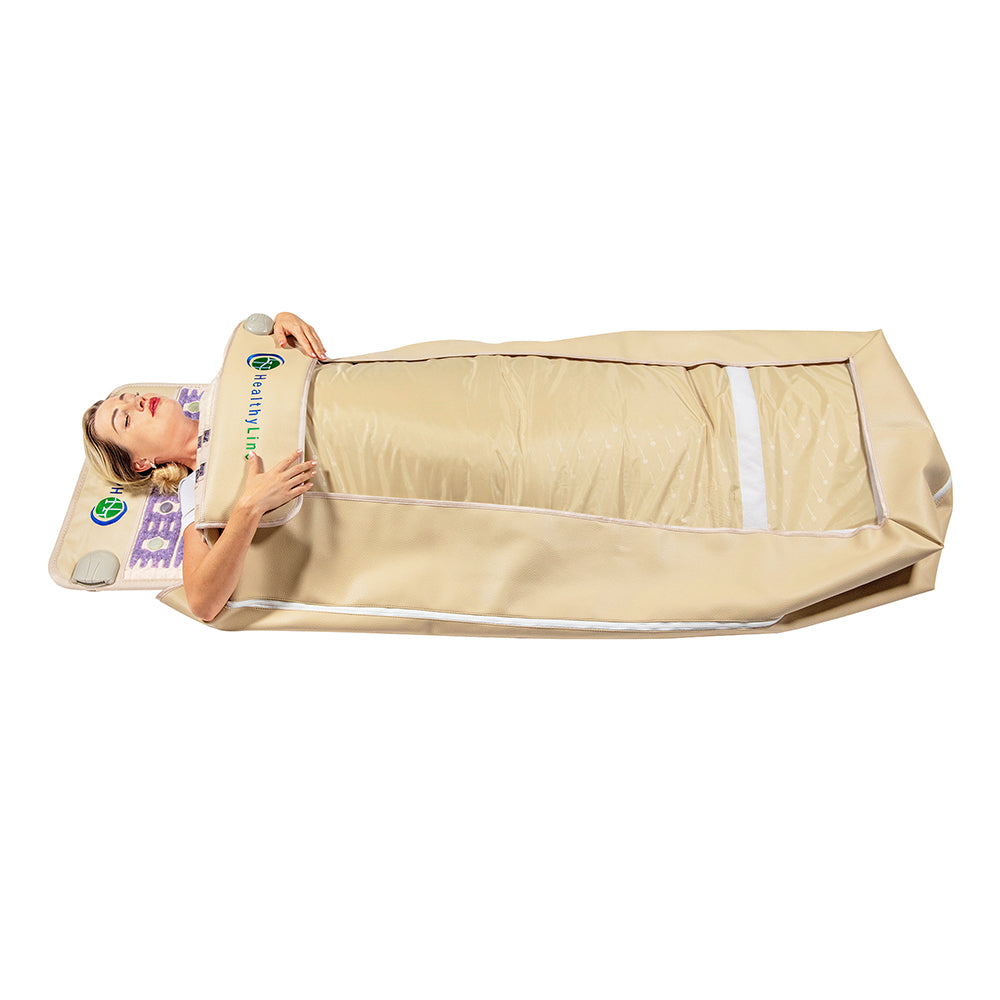 A person is experiencing ultimate relaxation wrapped in the 360 Wrap Set™ TAJ & SOFT Full 7224 - Photon PEMF InfraMat Pro® by HealthyLine. Their head is comfortably resting on a pillow, while the beige sauna blanket envelops their body entirely, offering soothing infrared therapy. Lying flat, they appear thoroughly at ease in this full-body experience.