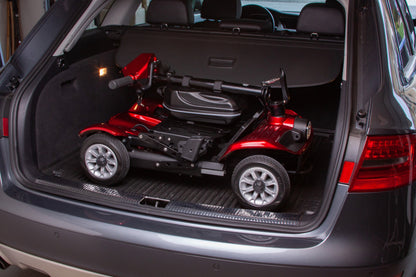 An EW-26 Folding Scooter by E-Wheels is securely placed inside the trunk of a gray SUV. The spacious compartment accommodates the scooter comfortably, highlighting the SUV's capability to transport lightweight mobility scooters efficiently due to its compact design and smart use of space.