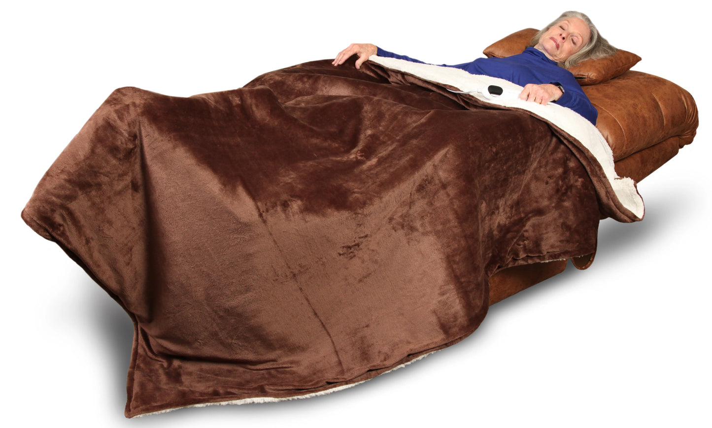 An elderly person reclines peacefully in a Perfect Sleep Chair by Journey Health & Life Style, wrapped in a large, soft brown blanket. With a relaxed expression on their face, they are dressed in a blue top and supported by a tan pillow. The dual motors provide optimal positioning beneath their head for maximum comfort.