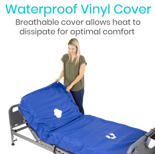 A woman stands beside a hospital bed with an 8” Alternating Pressure Mattress Cover by Vive Health. The blue, latex-free waterproof vinyl cover is partially lifted, highlighting its breathable design for optimal comfort and heat dissipation.