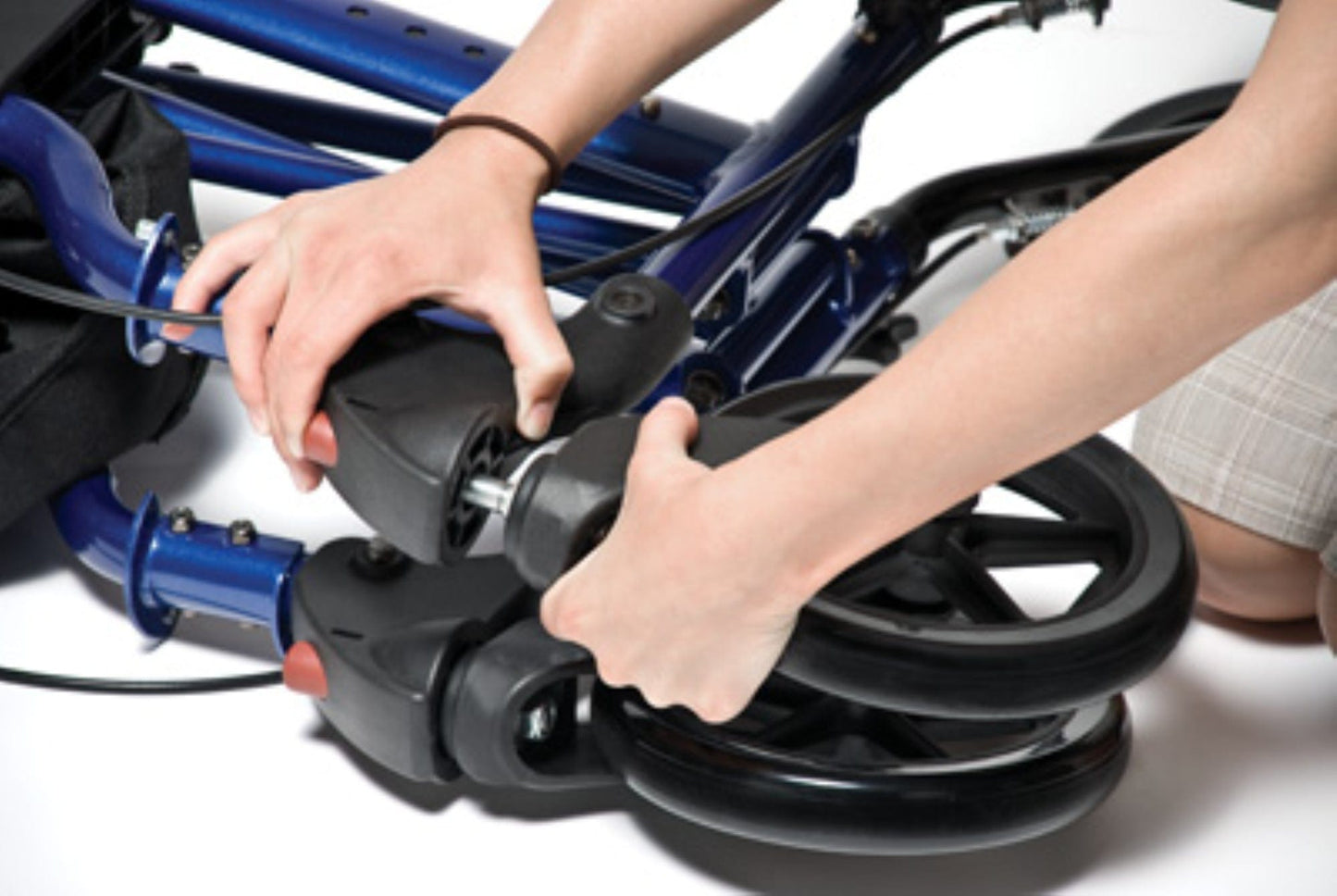 Close-up of hands adjusting the wheels on a Graham Field HybridLX Rollator Transport Chair. The individual secures a black plastic component, focusing on the connection between the frame and wheel in this lightweight design.