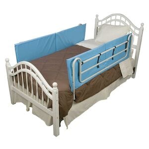 The setup includes a white bed adorned with a brown blanket and a white pillow, complemented by the Bed Rail Bumper Pads in blue from HealthSmart for enhanced safety. The frame is enhanced by decorative head and footboards, providing an elegant touch.