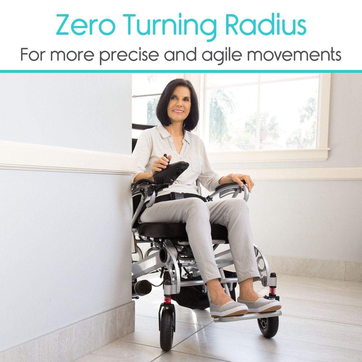 A woman in a Vive Health Power Wheelchair, featuring a modern dual-motor system, skillfully maneuvers through a corner in a well-lit room. She smiles while operating the joystick controller. The text above reads: "Zero Turning Radius for more precise and agile movements.