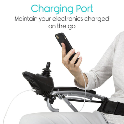 A person in a Vive Health Power WheelChair, equipped with a dual motor and built-in charging port, is holding a smartphone connected by a white cable. Text above reads: "Built-in Charging Port: Keep your electronics powered on the go while maneuvering effortlessly with the joystick controller.