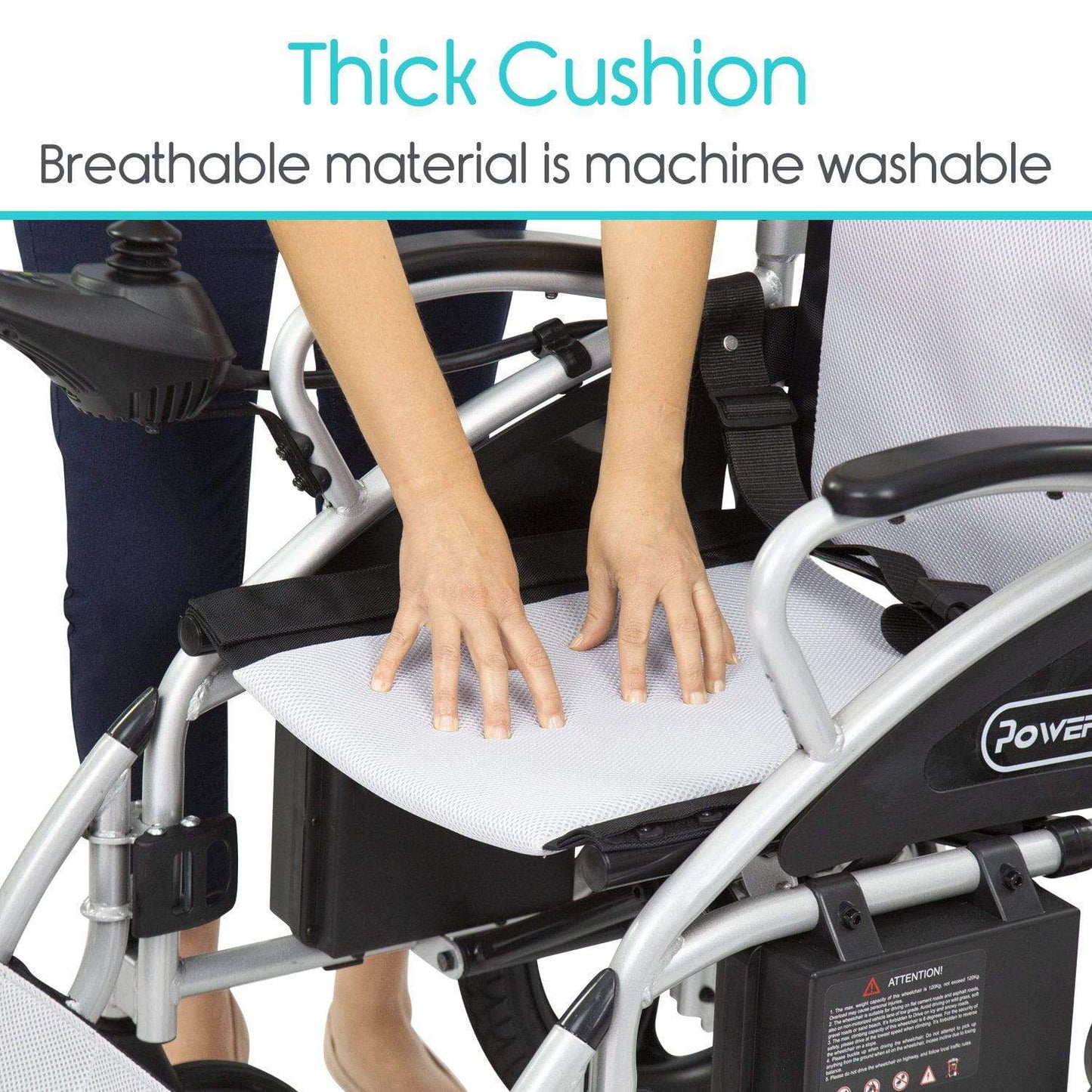 A person presses down on the thick cushion seat of a Compact Power Wheelchair by Vive Health. The white cushion is crafted from breathable, machine-washable material. Text above reads "Thick Cushion" and below, "Breathable material is machine washable.