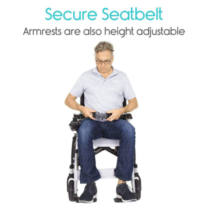 A person sitting in a Compact Power Wheelchair from Vive Health demonstrates the secure seatbelt feature. The text above highlights, "Secure Seatbelt. Armrests are also height adjustable." The individual is dressed in a light blue shirt and jeans.