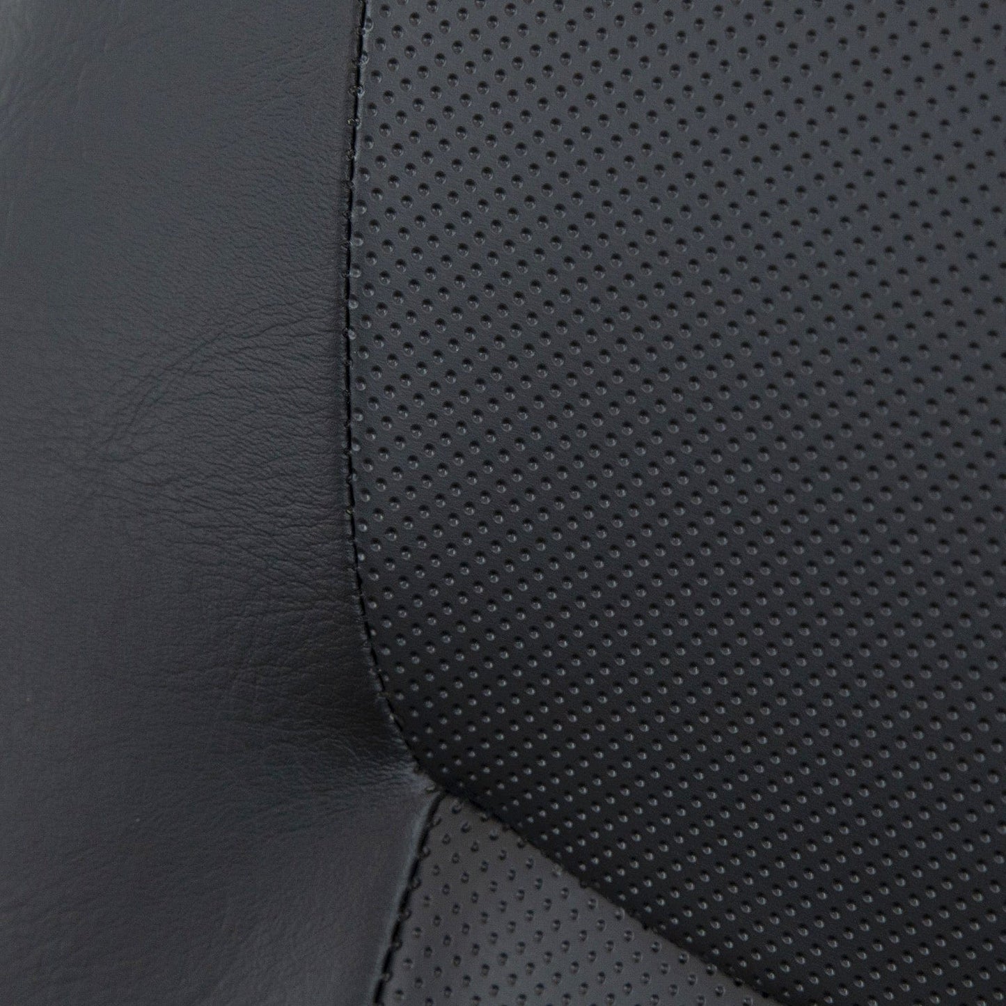 Close-up of a black leather car seat, echoing the sleek design of the Vive Health Electric Wheelchair Model V. It features two types of leather: one smooth and one perforated with small holes, adding textured contrast to the seat's surface.