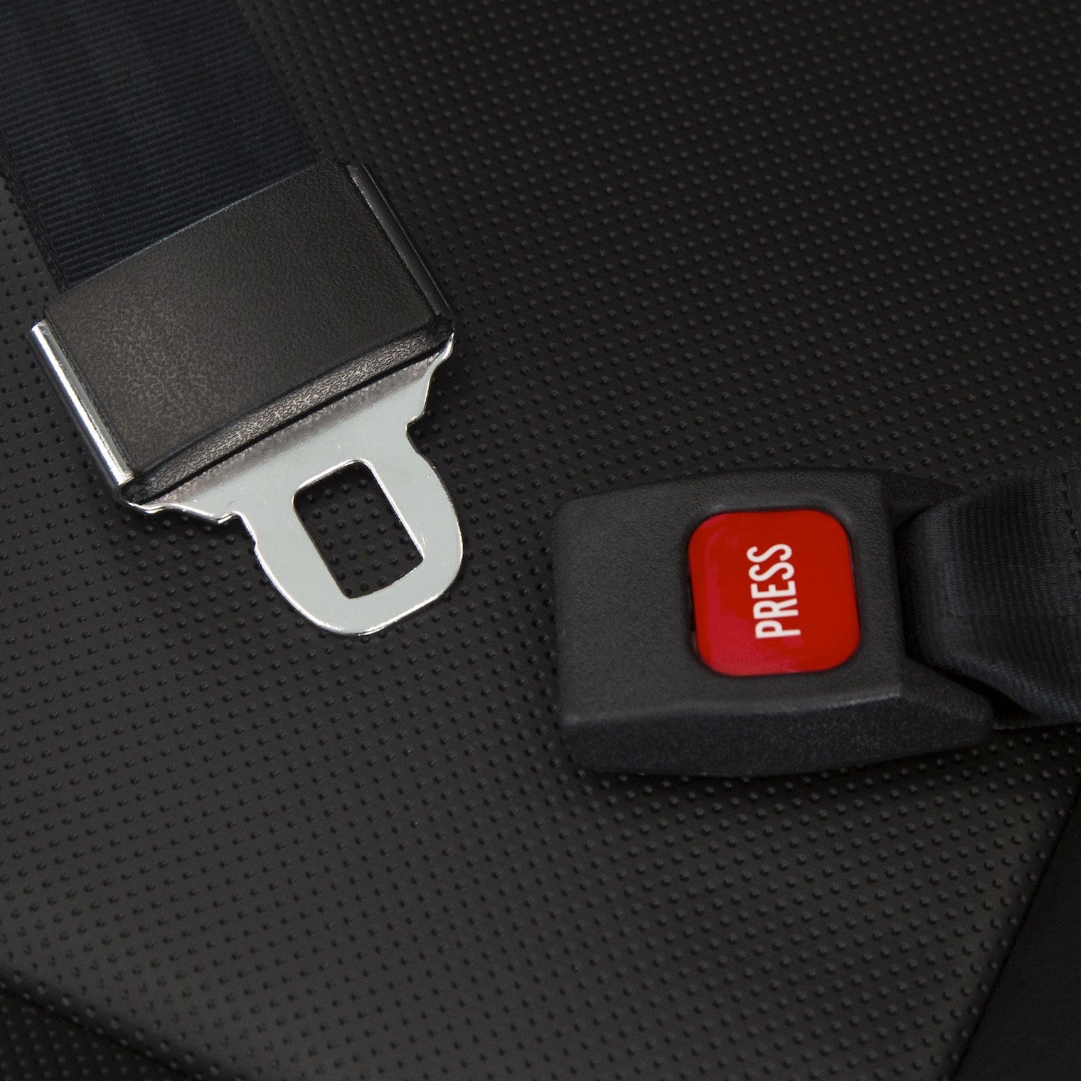 Close-up of a black seatbelt buckle and latch on a textured background, resembling the safety features in the Vive Health Electric Wheelchair Model: V. The metallic latch is flat, and the buckle has a red "PRESS" button for secure mobility.