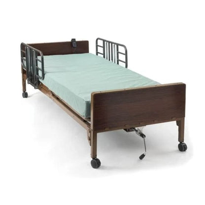 Introducing the Medline Bed Semi Electric Basic: This homecare bed includes side rails, a green mattress, and a wooden headboard and footboard. It features wheels for easy mobility and incorporates essential safety elements. The bed's simple yet functional design makes it ideal for both comfort and care.