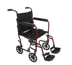 The Compass Health Transport Chair 19'' Aluminum is a light red chair featuring black cushioned armrests and small black wheels. It comes with footrests and offers enhanced comfort with a fabric seat and backrest.