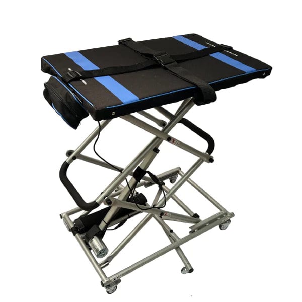 The So Lite Portable Lift by Journey Health & Lifestyle is a scissor lift table featuring a black and blue padded surface, a sturdy metal frame, locking caster wheels for easy mobility, and a black strap on top to secure items.